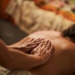 Close-up of masseur's hands applying oil on client's back during a relaxing massage therapy session, promoting wellness and relaxation