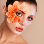 Portrait of beautiful young woman with makeup petals. Brunette woman with luxury makeup. Perfect skin. Eyelashes. Cosmetic eyeshadow