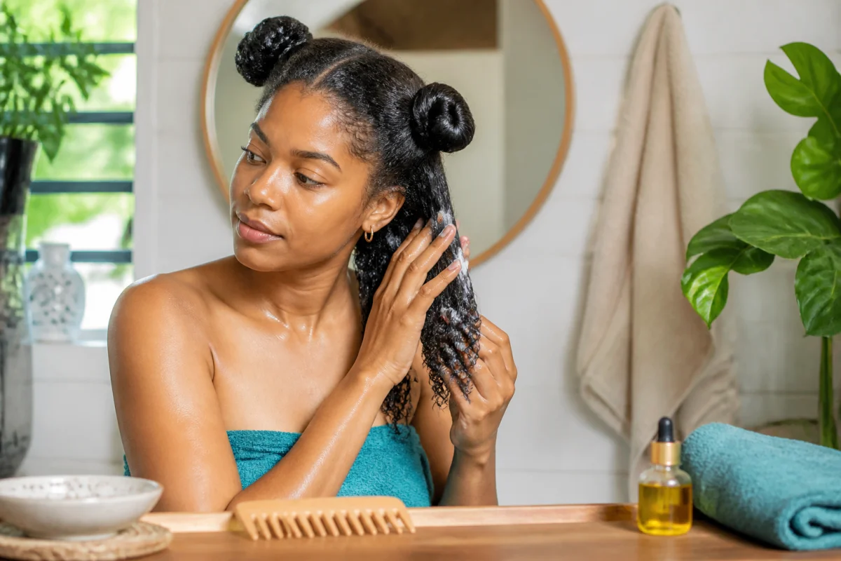 Soins naturels pour cheveux texturés : application d’un soin hydratant sur cheveux mouillés en quatre sections