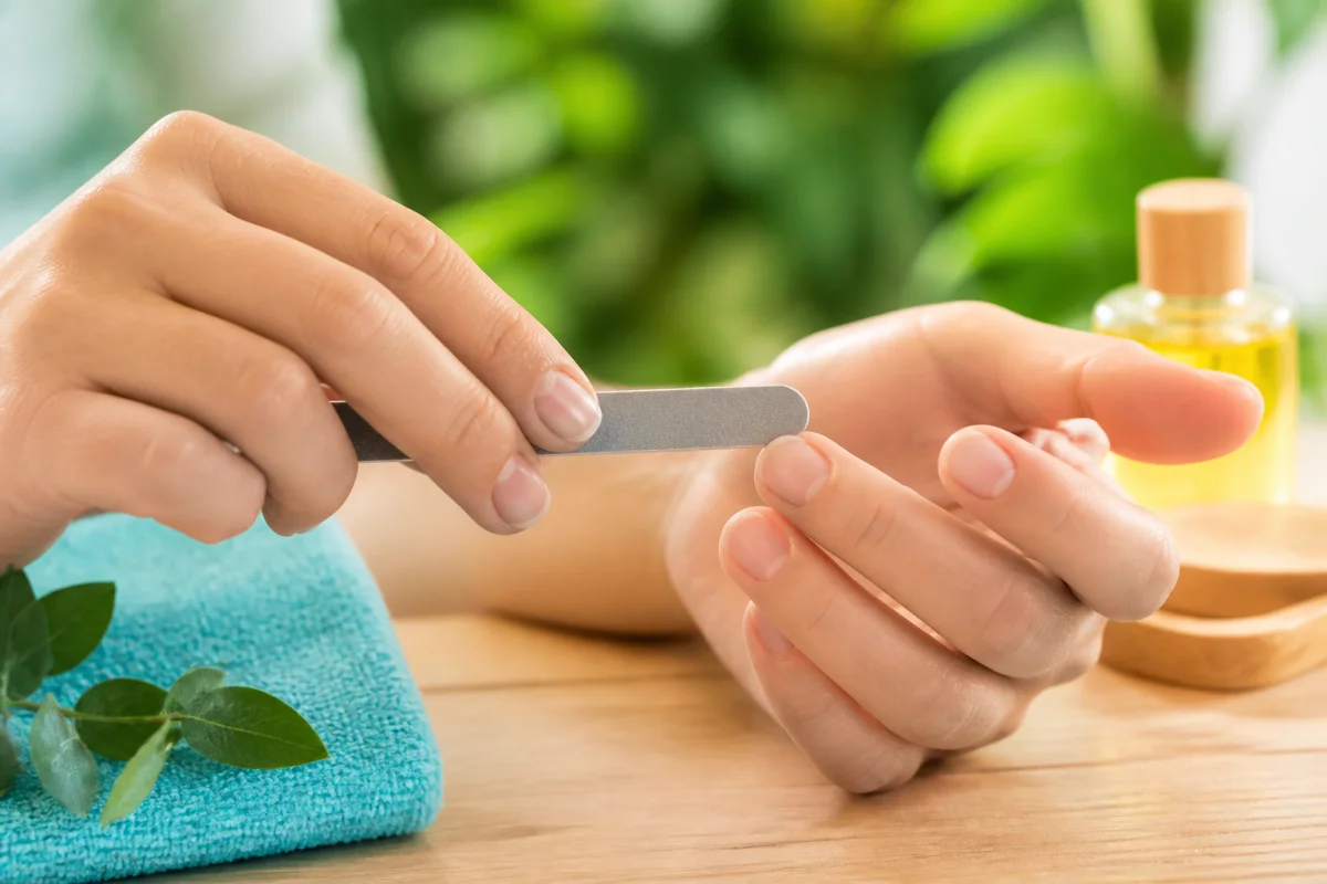 Soins des ongles naturels : mains limant délicatement un ongle naturel avec une lime fine